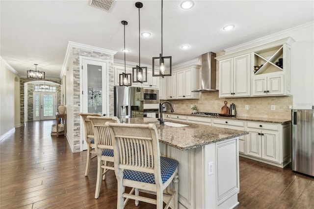 kitchen with visible vents, french doors, stainless steel appliances, wall chimney exhaust hood, and a sink