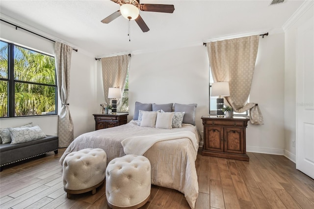 bedroom featuring visible vents, baseboards, ornamental molding, hardwood / wood-style flooring, and a ceiling fan