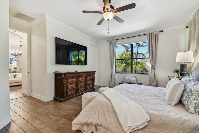 bedroom featuring wood finished floors, baseboards, visible vents, a textured ceiling, and crown molding