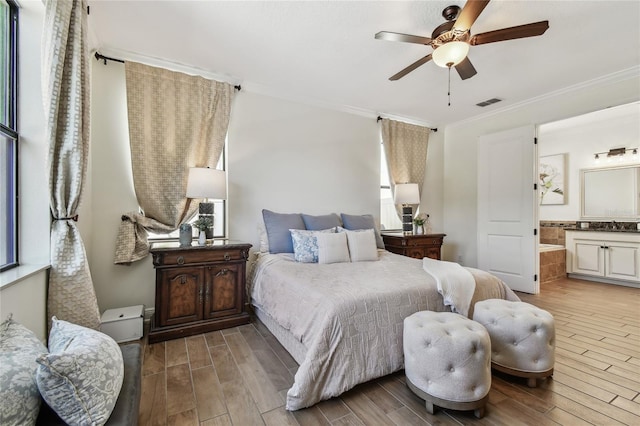 bedroom with connected bathroom, visible vents, wood finished floors, and ornamental molding