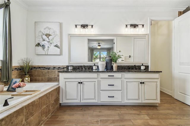 full bath featuring crown molding, a garden tub, double vanity, wood finished floors, and a sink