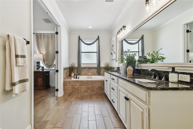 bathroom featuring visible vents, ornamental molding, wood finished floors, a bath, and vanity