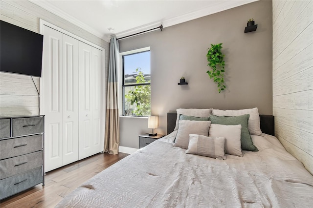 bedroom featuring a closet, crown molding, baseboards, and wood finished floors