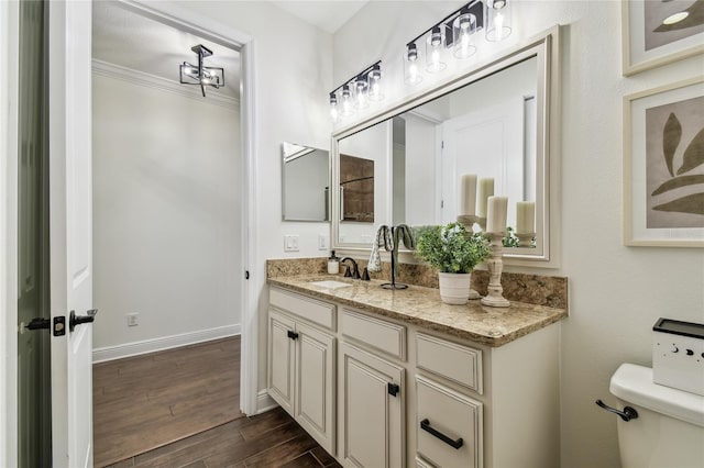 bathroom featuring crown molding, baseboards, toilet, wood finished floors, and vanity