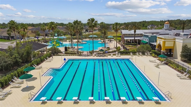 community pool featuring a patio area, fence, and a diving board