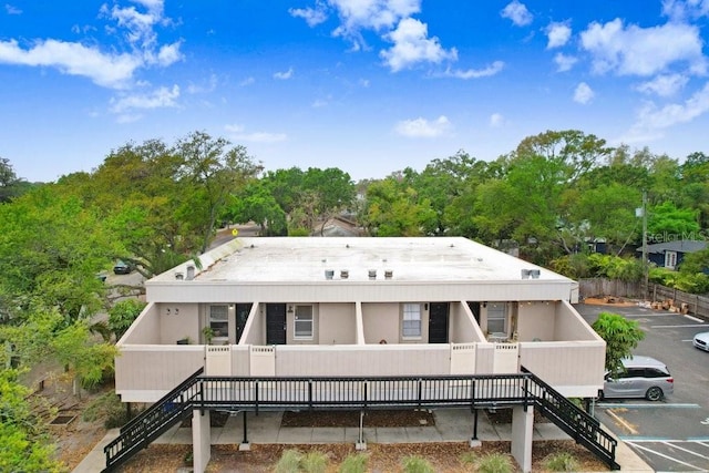 back of property with stairs and uncovered parking