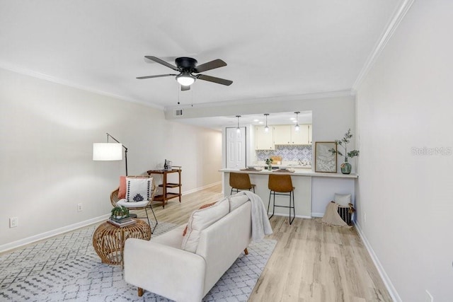 living room with light wood finished floors, ceiling fan, baseboards, and ornamental molding