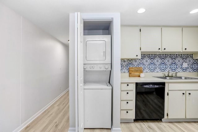 laundry room featuring light wood-style flooring, recessed lighting, stacked washer and clothes dryer, and a sink