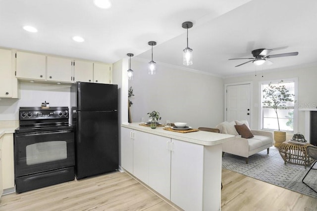 kitchen with light countertops, ornamental molding, a peninsula, light wood-style floors, and black appliances