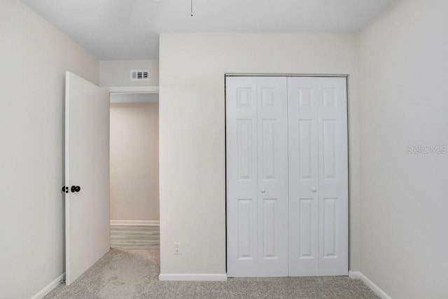 unfurnished bedroom featuring a closet, visible vents, baseboards, and carpet floors