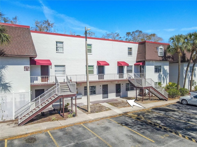 view of building exterior featuring stairway and uncovered parking