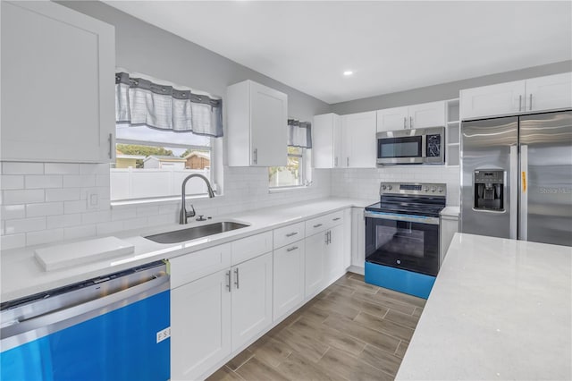 kitchen featuring a sink, light countertops, appliances with stainless steel finishes, white cabinetry, and tasteful backsplash