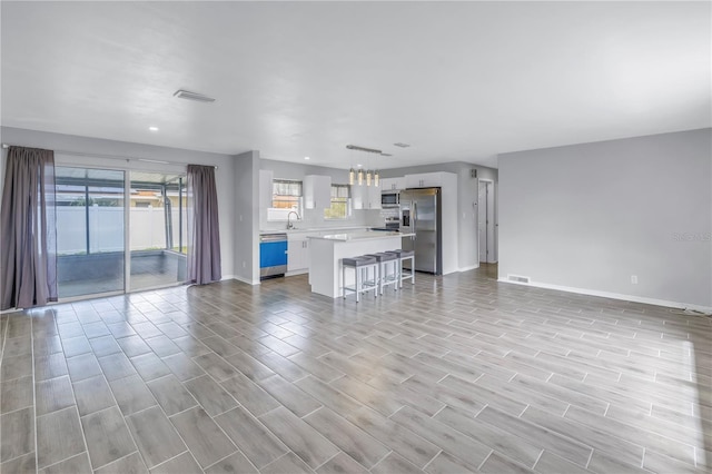 unfurnished living room featuring visible vents, a healthy amount of sunlight, and a sink