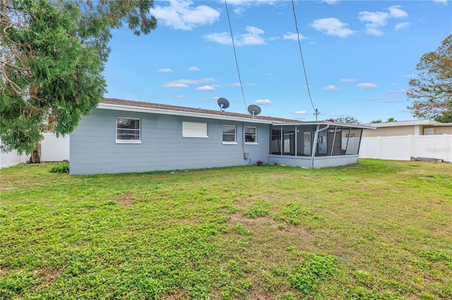 back of house featuring a yard, a fenced backyard, and a sunroom