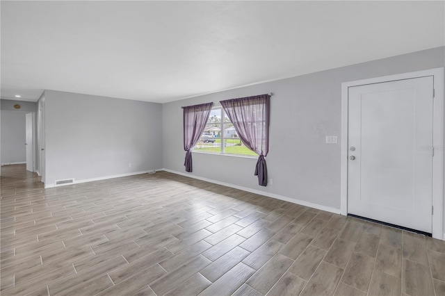 unfurnished living room with baseboards, visible vents, and wood tiled floor