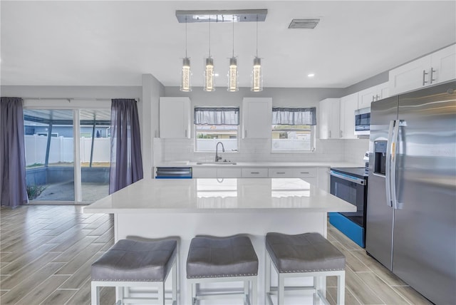 kitchen featuring a sink, a kitchen bar, backsplash, and appliances with stainless steel finishes