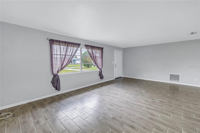 unfurnished room featuring visible vents, baseboards, and wood tiled floor