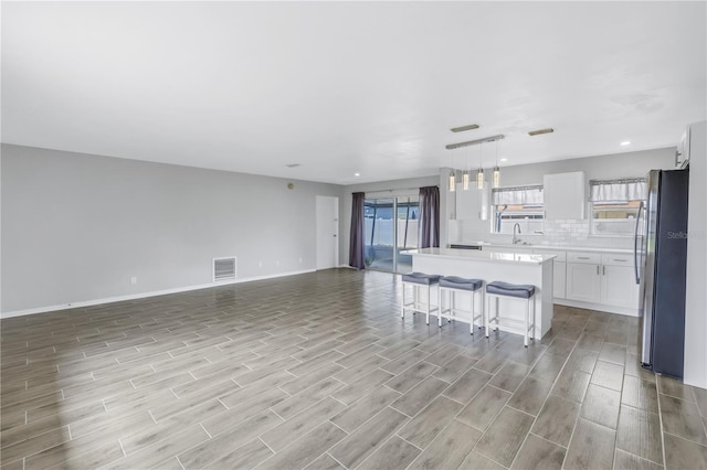 kitchen with visible vents, freestanding refrigerator, light countertops, open floor plan, and a center island