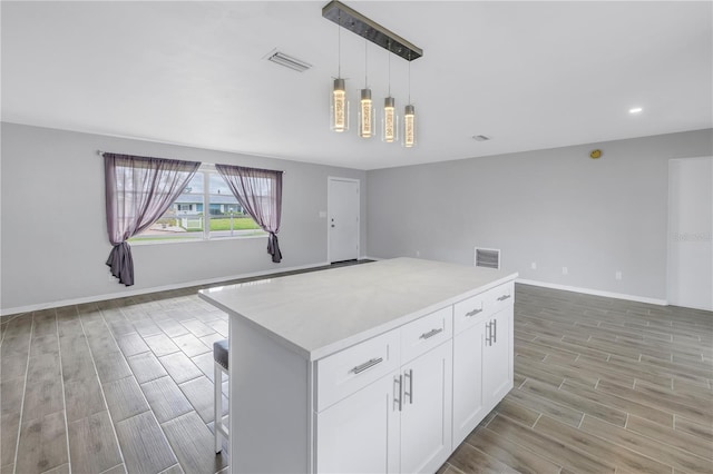 kitchen featuring visible vents, wood finish floors, light countertops, white cabinets, and open floor plan