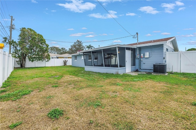 rear view of property with a gate, a fenced backyard, a yard, cooling unit, and a sunroom