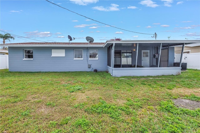 back of house featuring fence, a lawn, central AC unit, and a sunroom