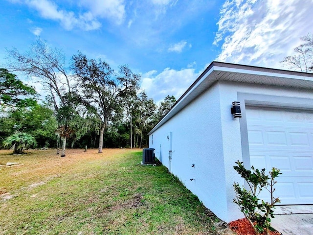 view of home's exterior featuring a garage, a yard, cooling unit, and stucco siding