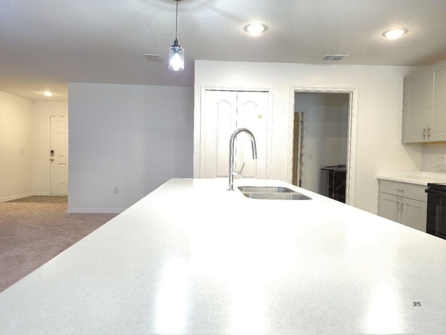 kitchen with visible vents, carpet floors, a sink, light countertops, and pendant lighting