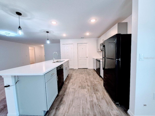 kitchen with a sink, light wood-type flooring, light countertops, black appliances, and a kitchen island with sink