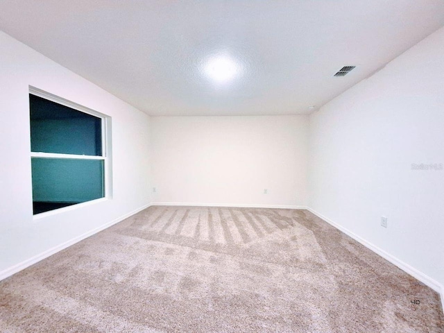 carpeted spare room with built in shelves, baseboards, and visible vents