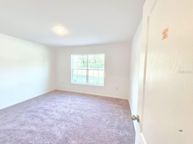 carpeted spare room with baseboards