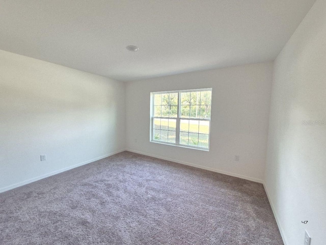 carpeted spare room with baseboards