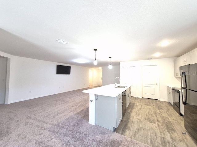 kitchen with visible vents, a center island with sink, a sink, open floor plan, and light countertops