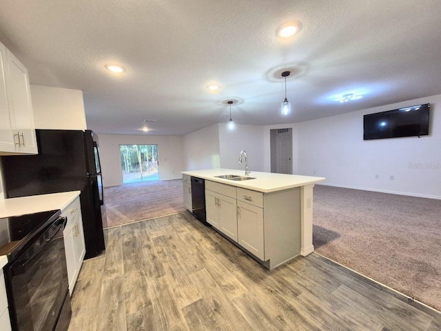 kitchen featuring black appliances, light carpet, open floor plan, and a sink