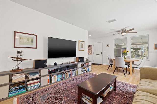 living area featuring visible vents, wood finished floors, and a ceiling fan