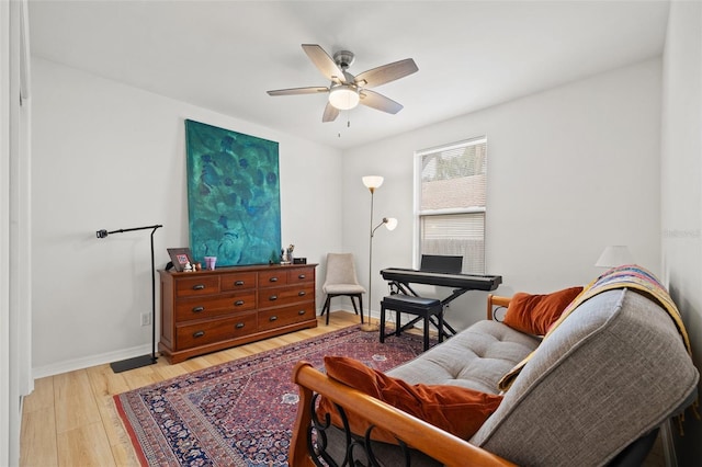 living area with baseboards, light wood-type flooring, and a ceiling fan