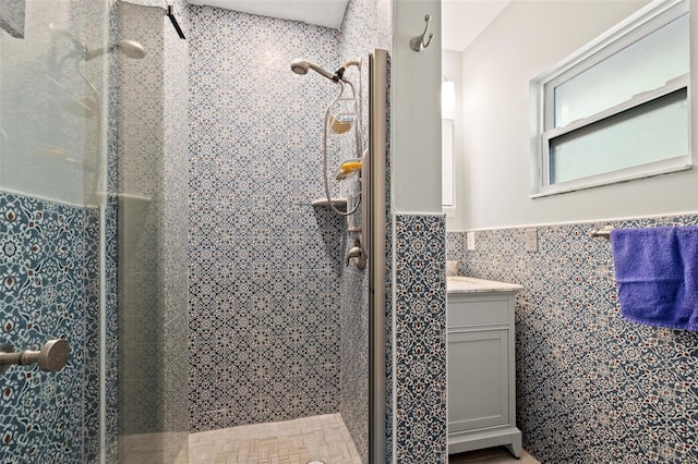 bathroom featuring vanity, tile walls, a stall shower, and wainscoting