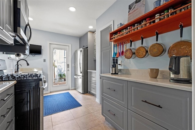 kitchen with light tile patterned floors, recessed lighting, gray cabinets, appliances with stainless steel finishes, and open shelves