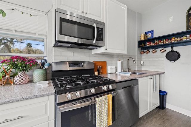 kitchen with tasteful backsplash, white cabinetry, stainless steel appliances, and a sink