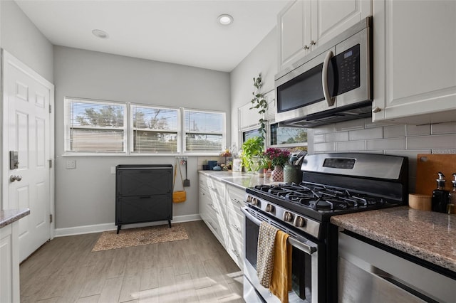 kitchen with decorative backsplash, plenty of natural light, white cabinetry, and appliances with stainless steel finishes