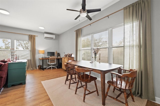 dining room with a ceiling fan, light wood-type flooring, and a wall mounted air conditioner