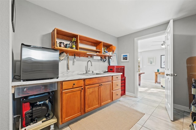 kitchen featuring baseboards, open shelves, light tile patterned flooring, a sink, and brown cabinets