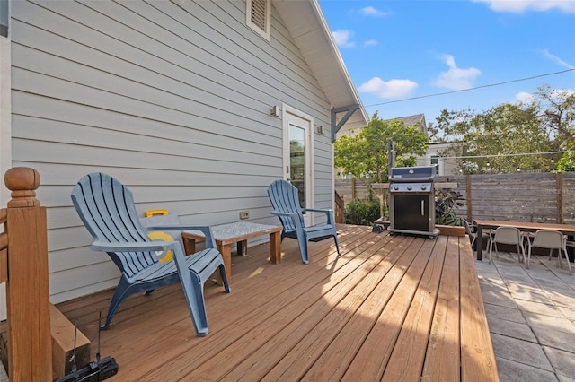 deck featuring outdoor dining area, fence, and a grill