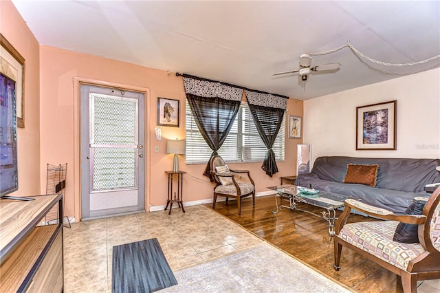 living room with wood finished floors, a ceiling fan, and baseboards