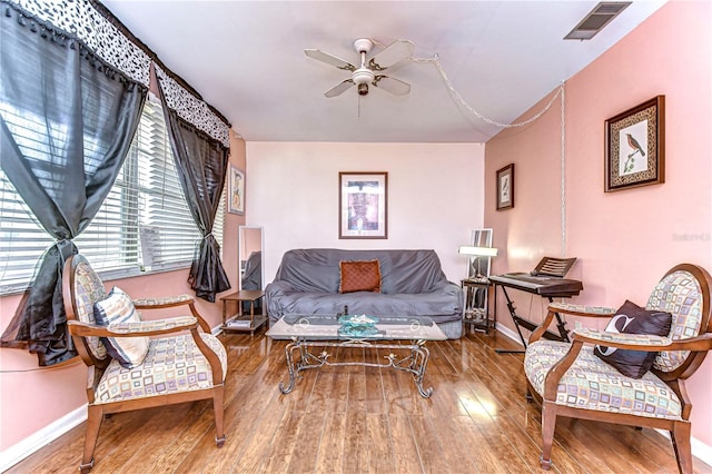 living room featuring visible vents, baseboards, a ceiling fan, and hardwood / wood-style flooring