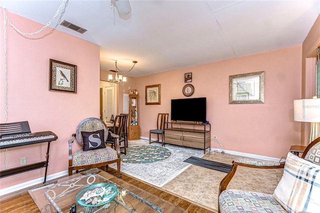 living room featuring an inviting chandelier, wood finished floors, baseboards, and visible vents