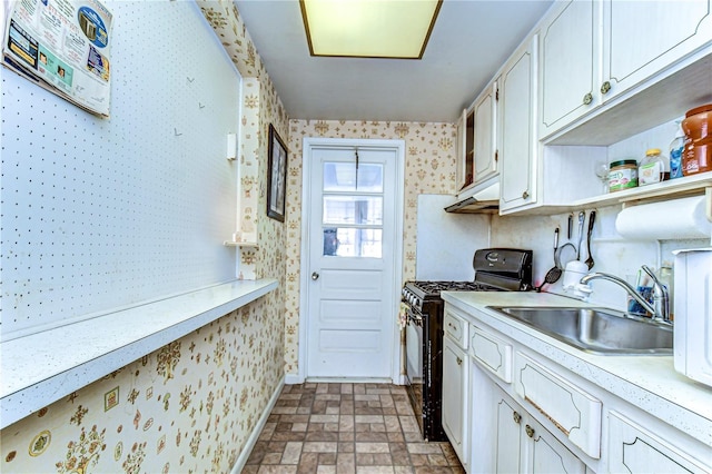 kitchen featuring wallpapered walls, light countertops, black range with gas cooktop, white cabinetry, and a sink