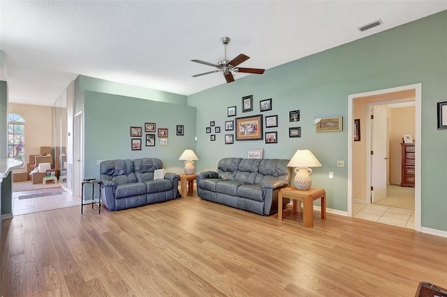 living area featuring visible vents, baseboards, light wood-type flooring, and a ceiling fan