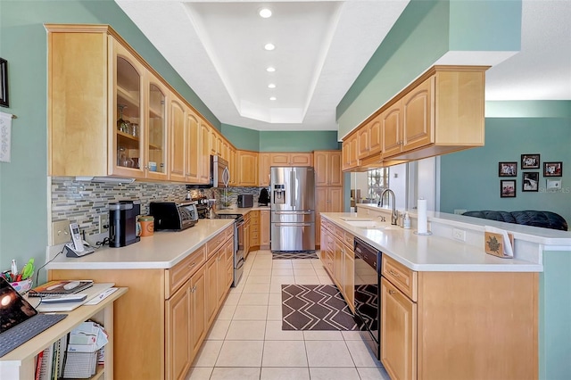 kitchen featuring light brown cabinetry, a tray ceiling, appliances with stainless steel finishes, and a sink