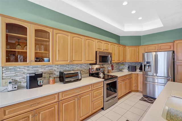 kitchen featuring light tile patterned floors, light brown cabinets, stainless steel appliances, glass insert cabinets, and tasteful backsplash