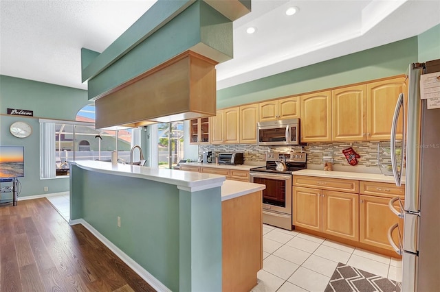 kitchen with light countertops, light brown cabinets, tasteful backsplash, and stainless steel appliances